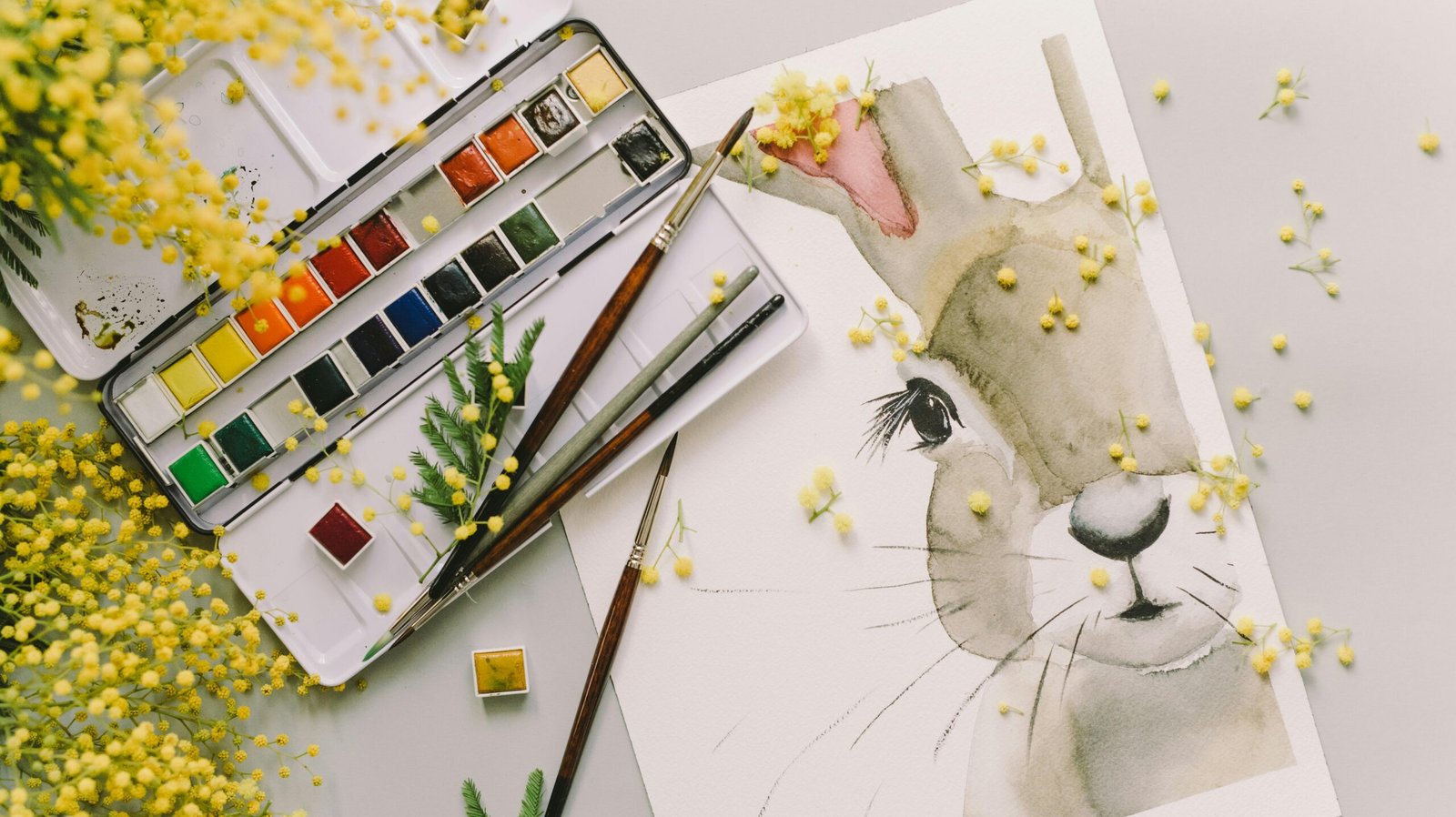 Charming watercolor painting of an Easter bunny surrounded by vibrant mimosa flowers and a color palette.